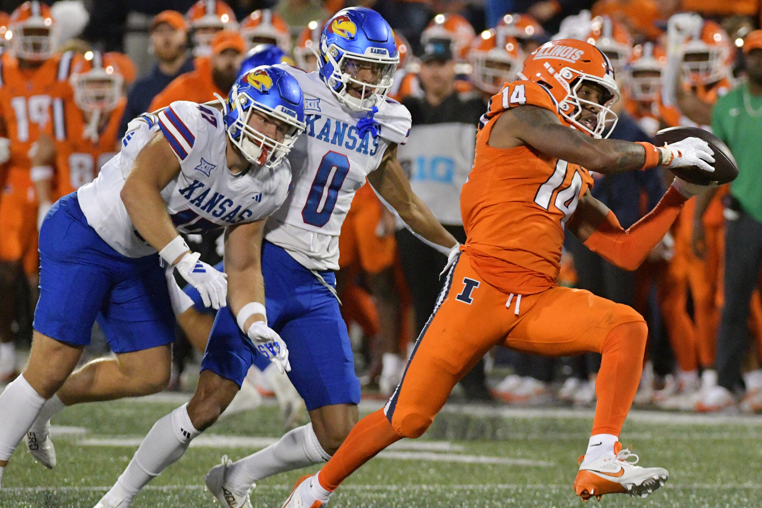 Sep 7, 2024; Champaign, Illinois, USA; Illinois Fighting Illini defensive back Xavier Scott (14) intercepts the ball in front of Kansas Jayhawks wide receiver Quentin Skinner (0) during the first half at Memorial Stadium. Mandatory Credit: Ron Johnson-Imagn Images