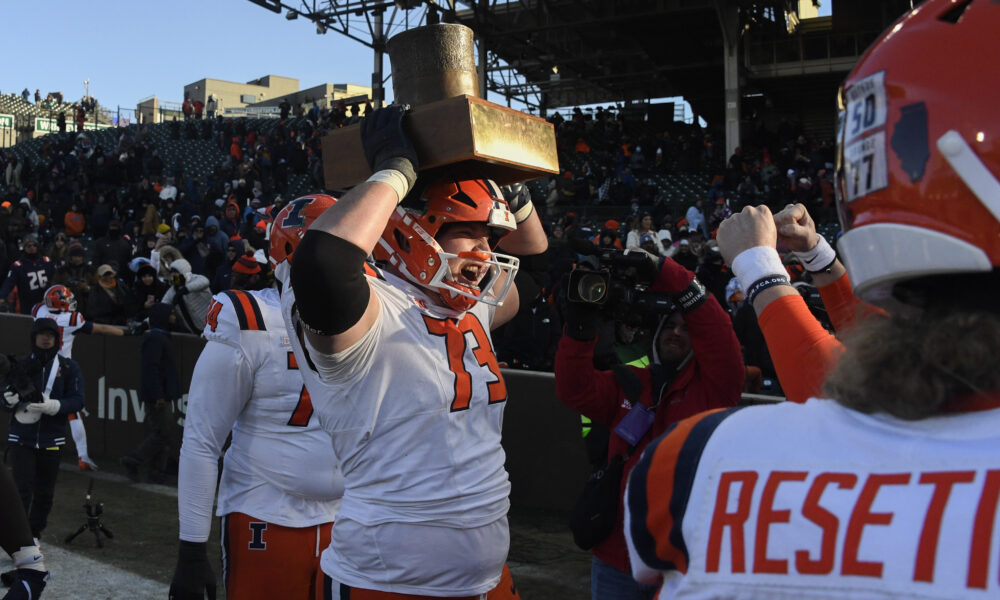 Illinois Football lineman holds up the Land of Lincoln trophy.