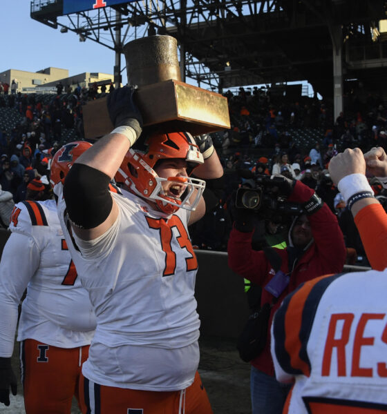 Illinois Football lineman holds up the Land of Lincoln trophy.