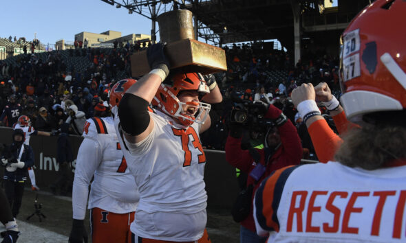 Illinois Football lineman holds up the Land of Lincoln trophy.