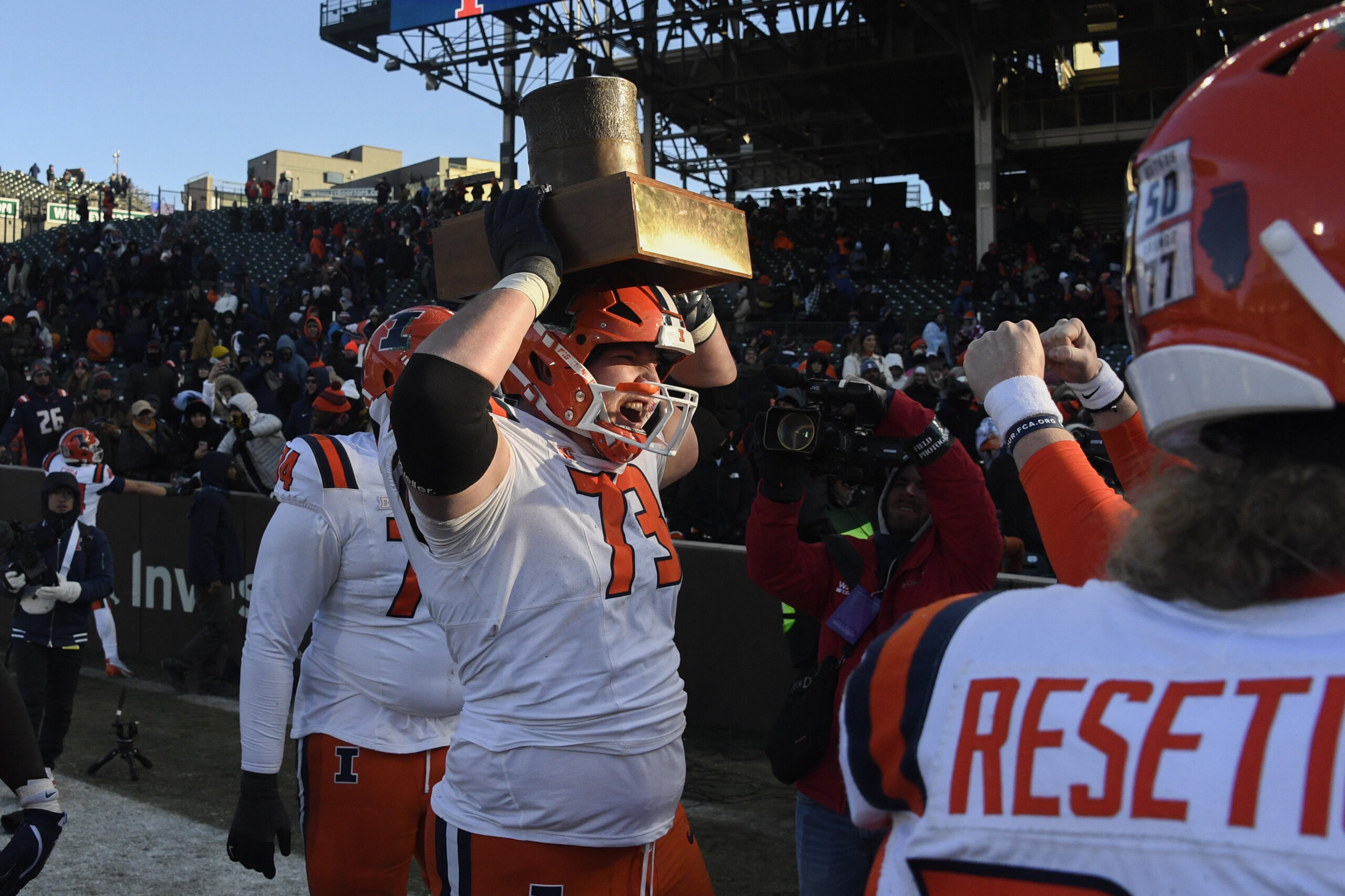 Illinois Football lineman holds up the Land of Lincoln trophy.